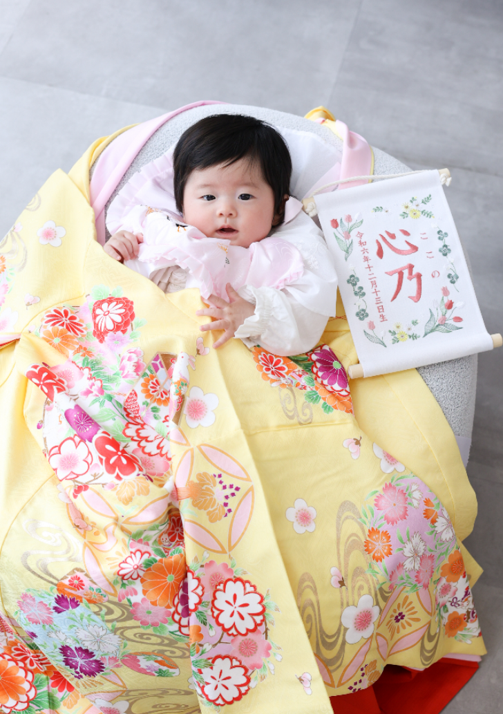 黄色の産着をかけられた赤ちゃん